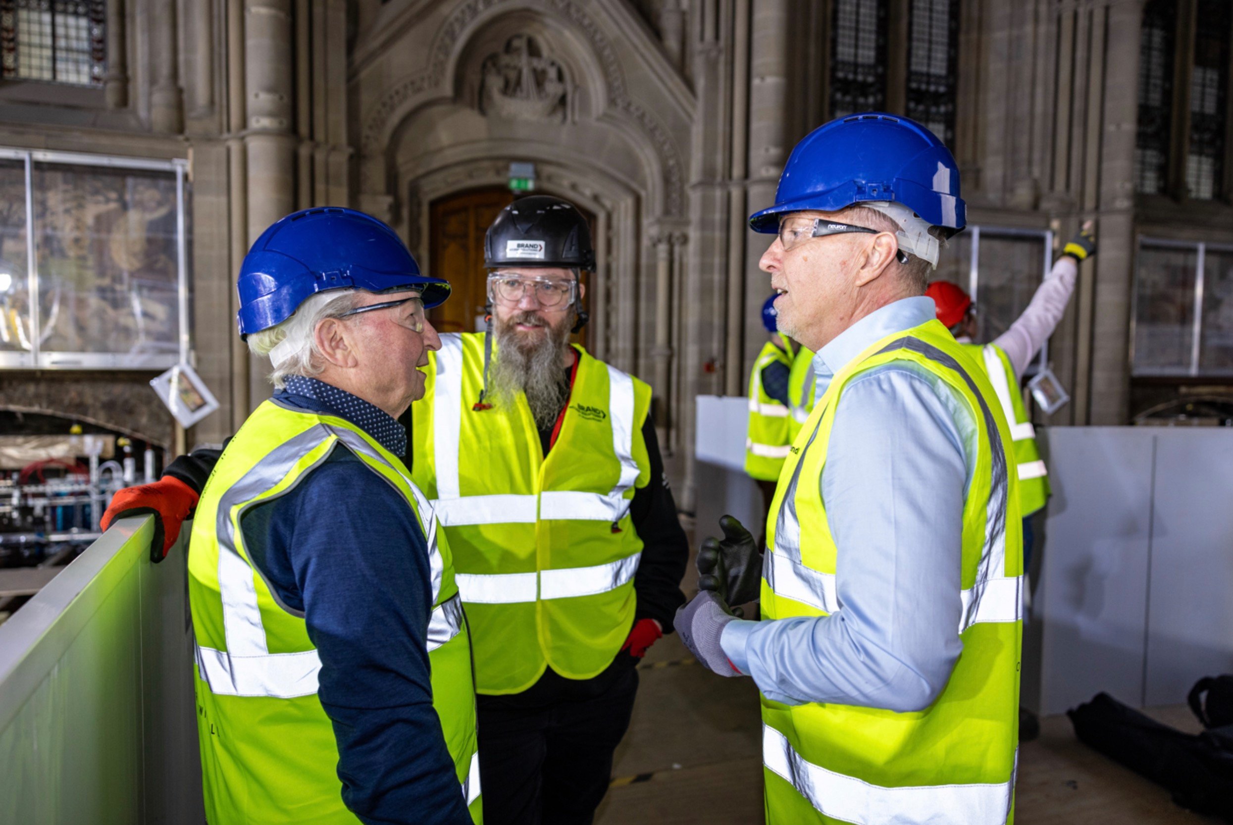 Men in High Visibility Jackets having a conversation in an old building